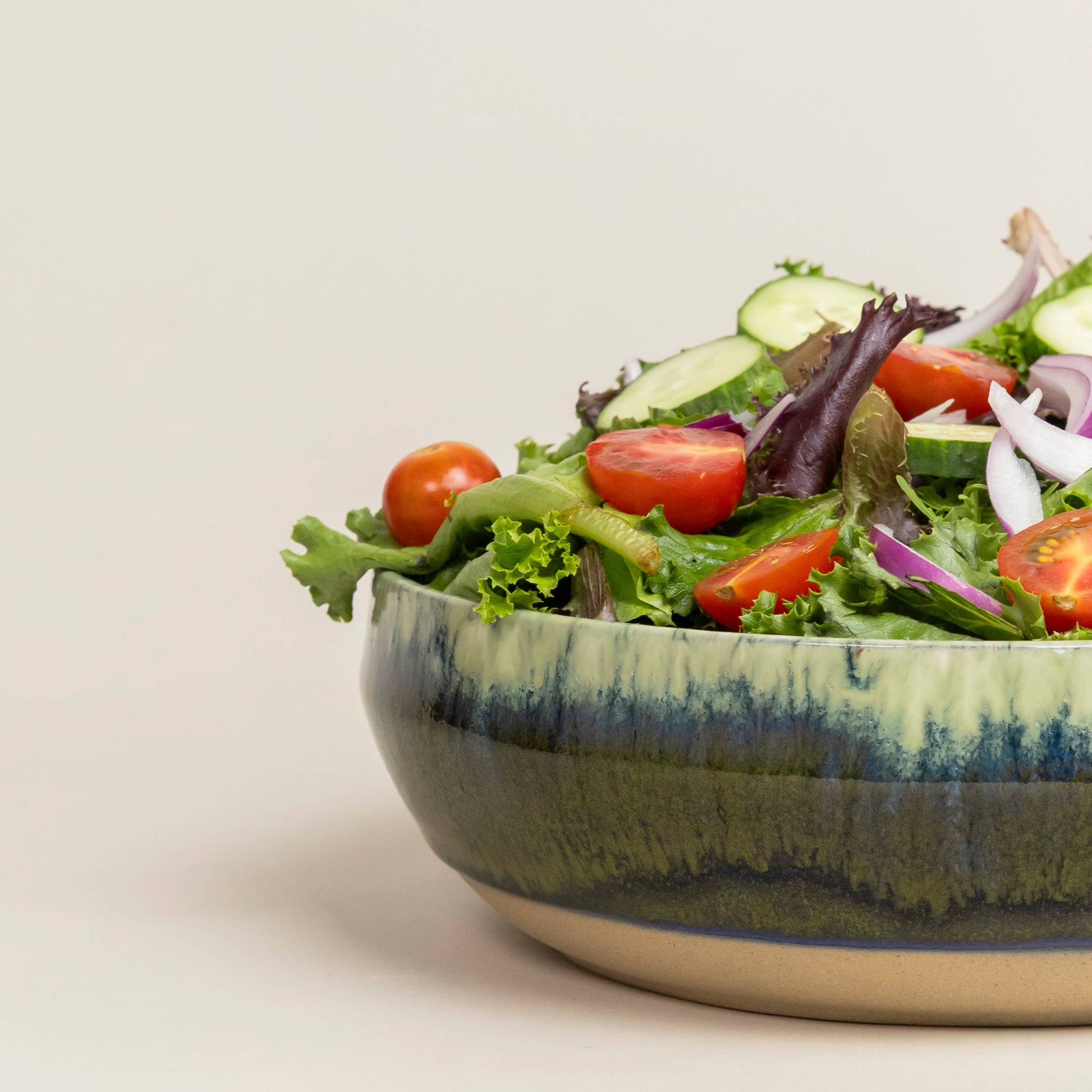 Green salad in a ceramic bowl on a light background