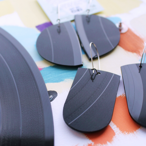 Vinyl record-themed earrings on a colorful background with text about the original vinyl record.