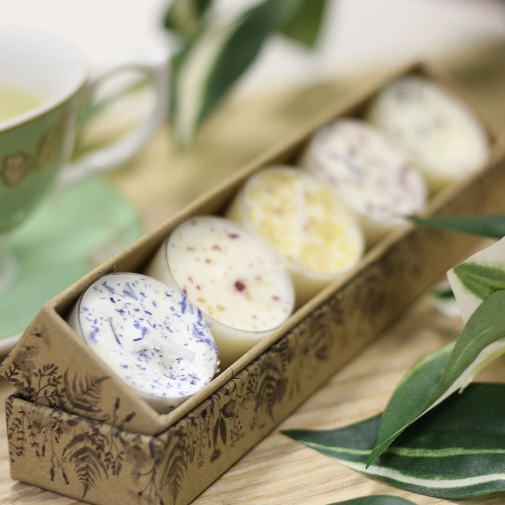 Bath bombs in a decorative box with a cup of tea and green leaves on a wooden surface