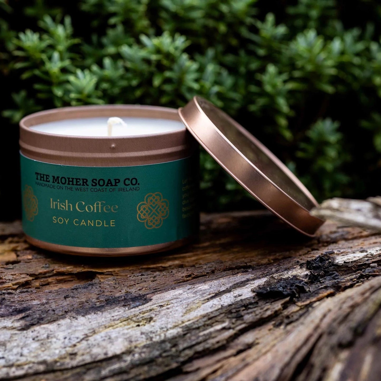 Candle from The Moher Soap Co. on a wooden surface with greenery in the background