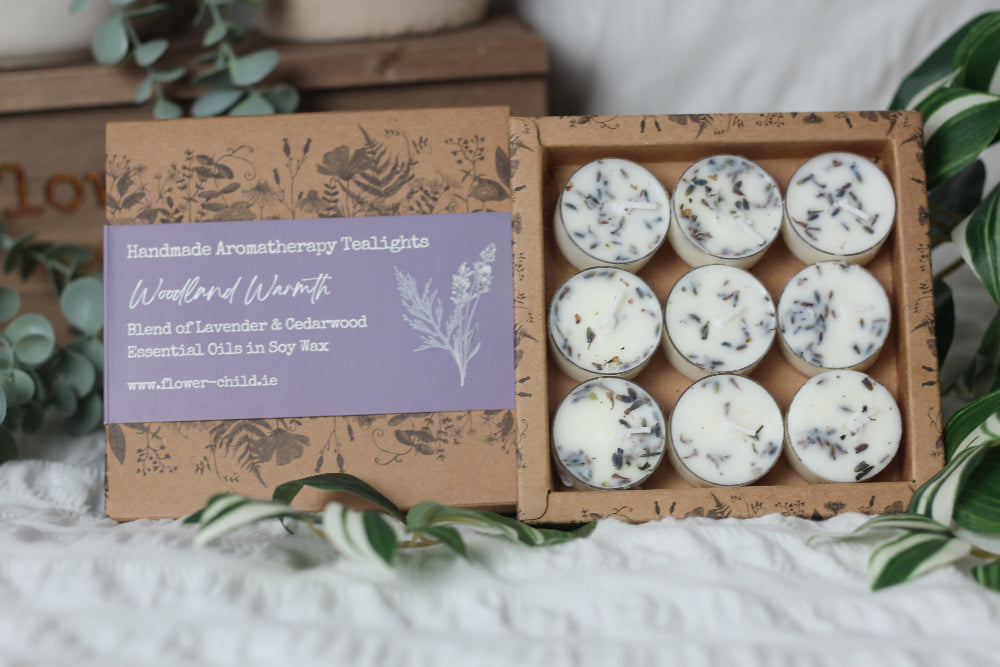 Box of Handmade Aromatherapy Tealights with a label on a white surface with greenery.