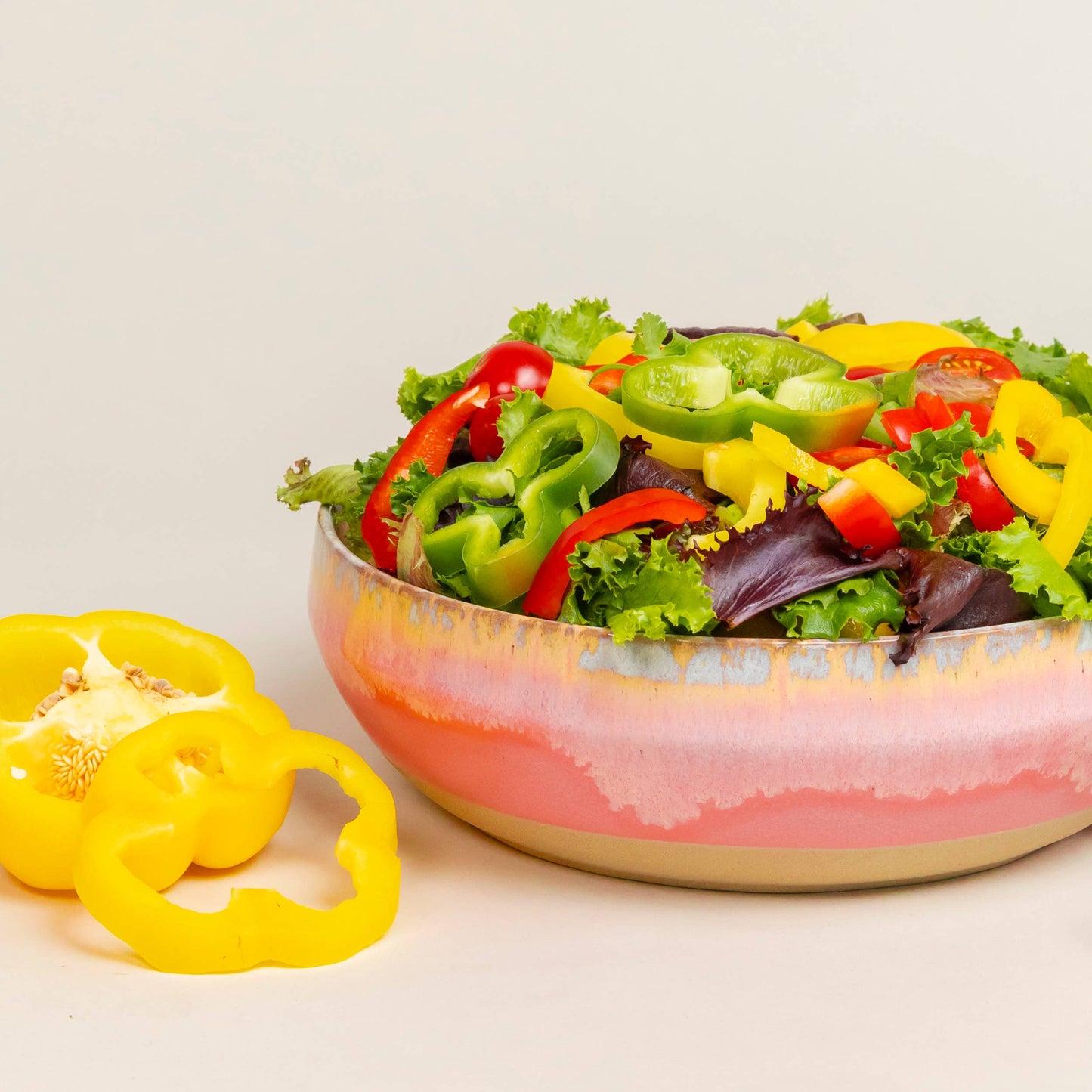 Colorful salad in a pink bowl with bell peppers on a light background