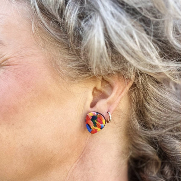Close-up of a person wearing a colorful earring with another earring in the background.