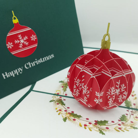 Red Christmas ball ornament with white patterns on a green card with 'Happy Christmas' text.