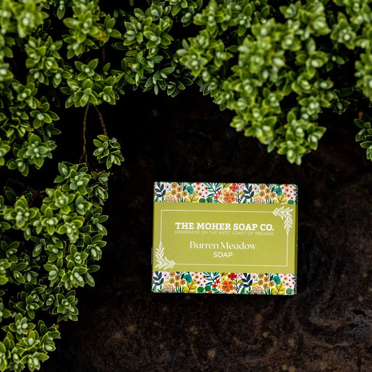Bar of soap from The Mohr Soap Co. with a colorful label on a dark background with green foliage.