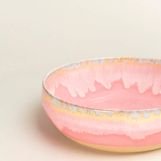 Pink ceramic bowl with gold rim on a light beige background