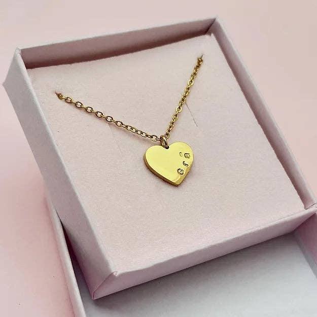 Gold heart-shaped necklace in a pink box on a light pink background