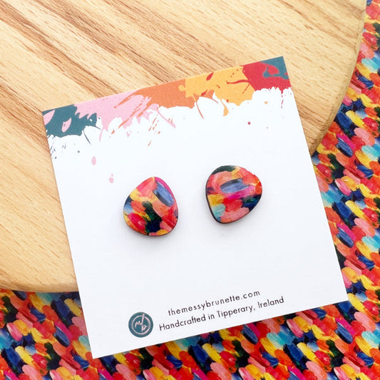 Colorful round earrings on a branded card with a colorful woven surface underneath.