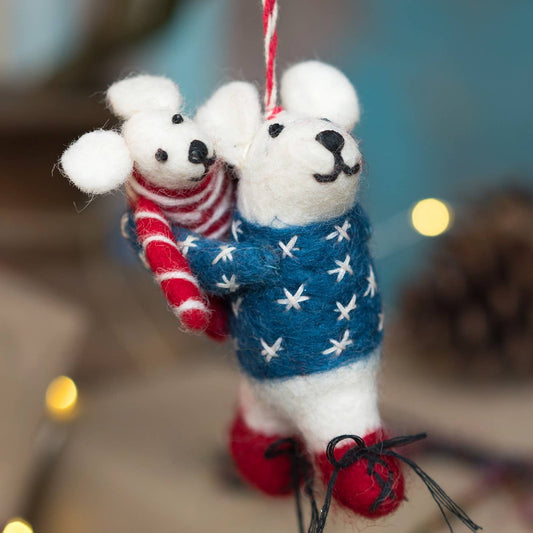 Decorative ornament of two white bears, one holding a red and white striped bear, against a blurred natural background.