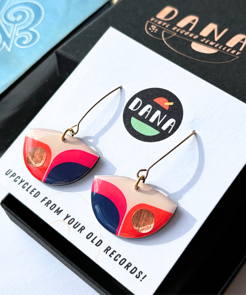 Colorful earrings on a card with 'Dana' branding and text about upcycling from old records.