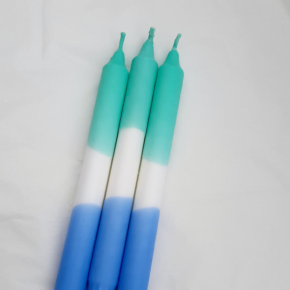 A set of three dip-dye candles with blue and green colors on a white background.